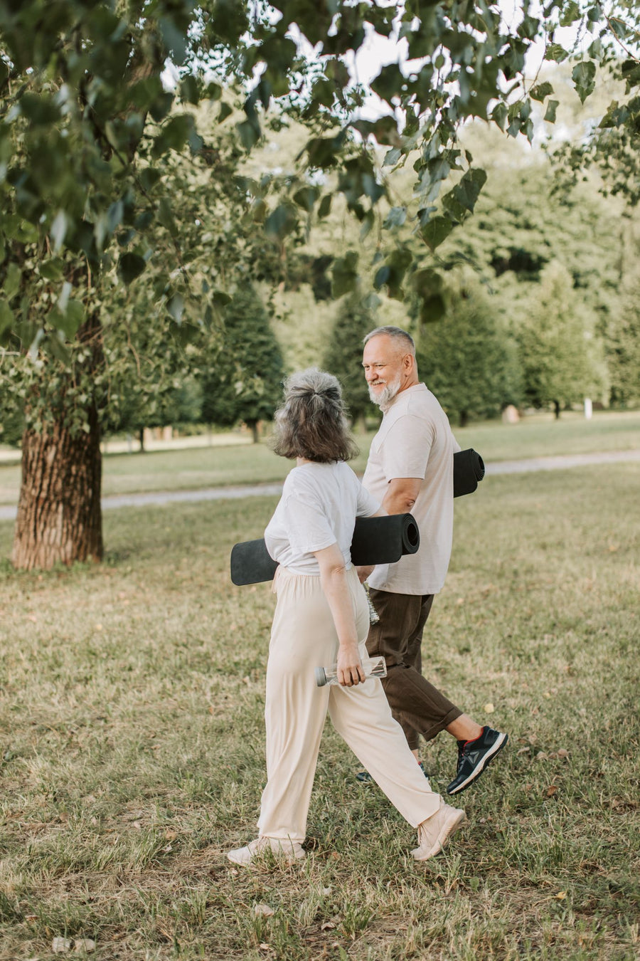 Couple marchant dans un parc verdoyant avec des tapis de yoga