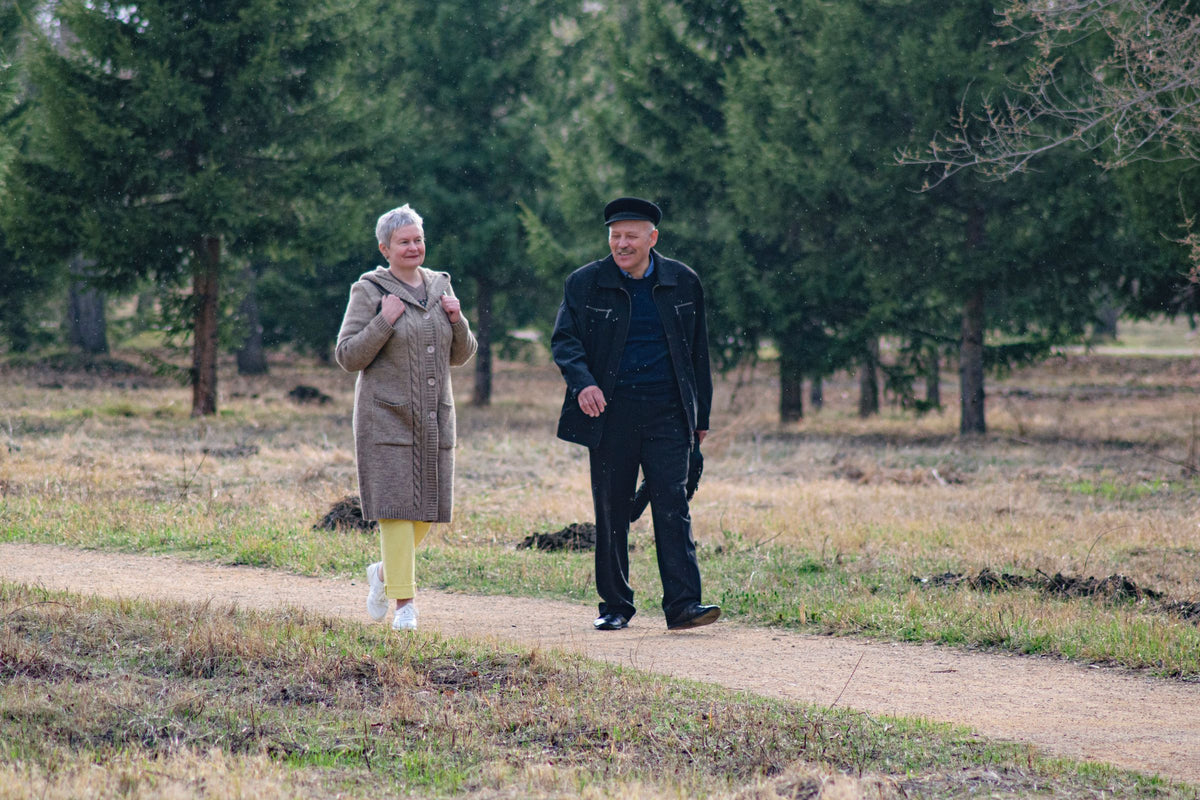 Older couple walking and smiling along a park path